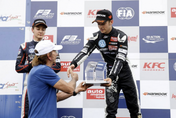 Charles Leclerc being handed the trophy from the great Emerson Fittipaldi