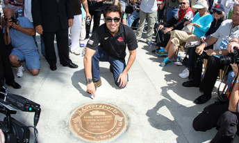 Dario Franchitti kneeling in front of the pavement medallion struck in his honour