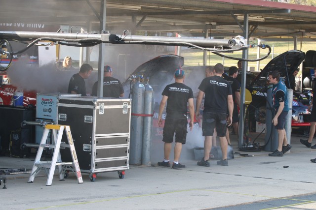 Triple Eight crew members assess the damage following a small fire on Craig Lowndes