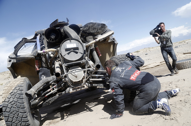 Loeb inspects the damage to his  2008 DKR Peugeot which has dashed his chances of outright victory
