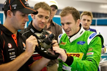 Jamie Whincup, Will Davison and Paul Dumbrell inspect the steering wheel of the Minardi Formula One two-seater in Abu Dhabi